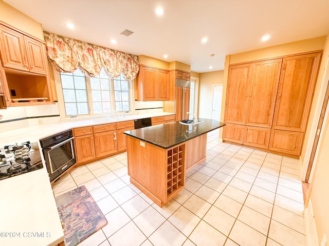 kitchen featuring black appliances, sink, light tile patterned floors, and a center island