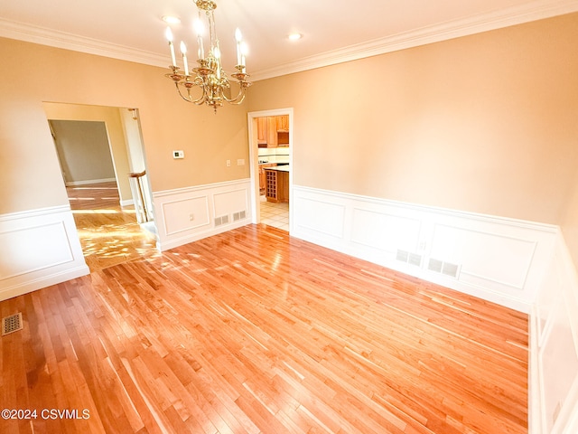 spare room with light hardwood / wood-style flooring, a chandelier, and crown molding