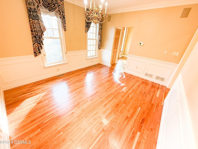 spare room with a chandelier, hardwood / wood-style flooring, and crown molding