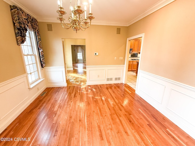 unfurnished dining area featuring light hardwood / wood-style floors, a chandelier, and crown molding