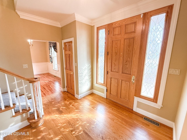 entryway with light wood-type flooring, a healthy amount of sunlight, and crown molding