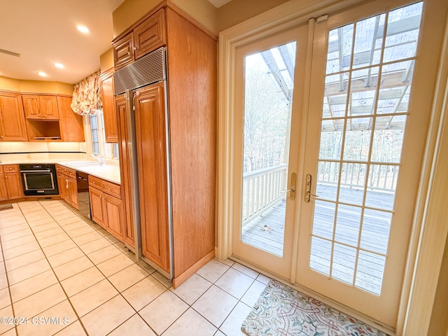 kitchen featuring sink, light tile patterned floors, black appliances, and french doors