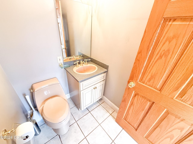 bathroom with toilet, vanity, and tile patterned flooring