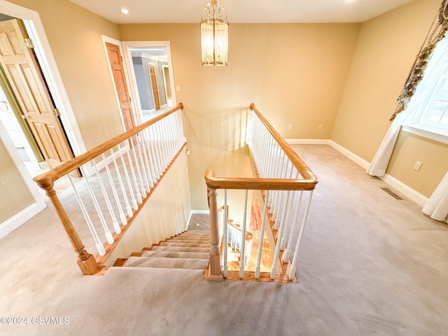 stairs featuring carpet flooring and a notable chandelier