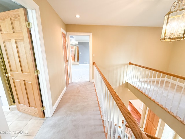 corridor featuring light colored carpet and an inviting chandelier