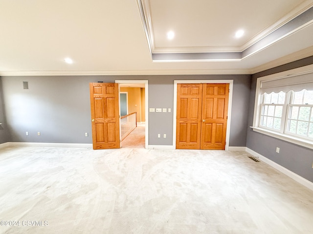 unfurnished bedroom with carpet flooring, a raised ceiling, and ornamental molding