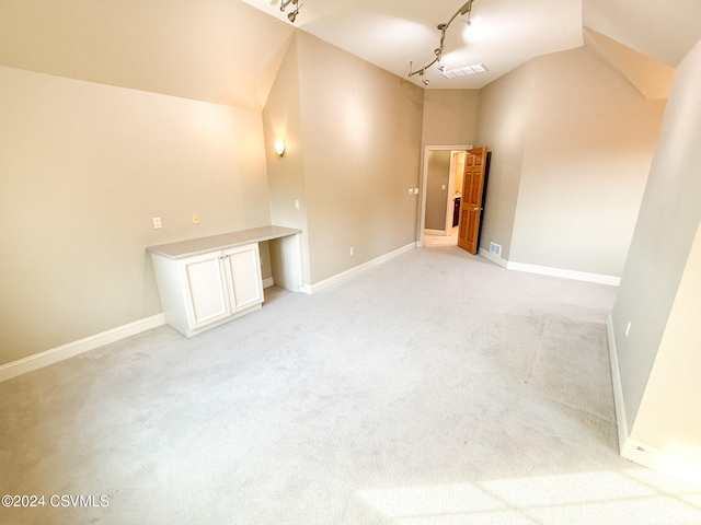 interior space featuring light colored carpet, track lighting, and lofted ceiling