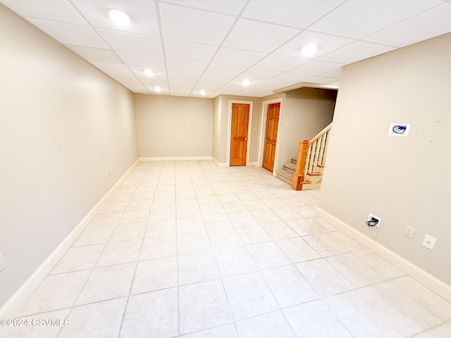 basement with a paneled ceiling and light tile patterned floors