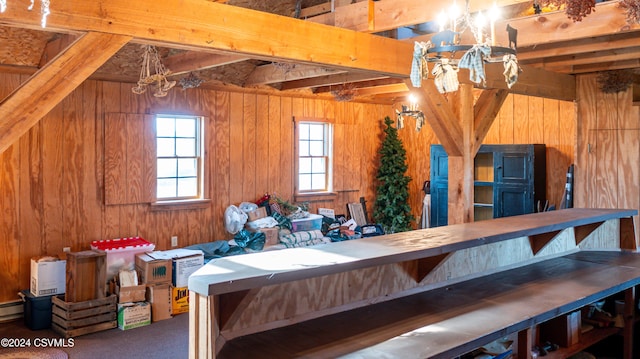 interior space featuring an inviting chandelier, wooden walls, and beamed ceiling