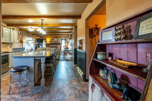 kitchen featuring a breakfast bar, decorative light fixtures, backsplash, a center island, and beam ceiling