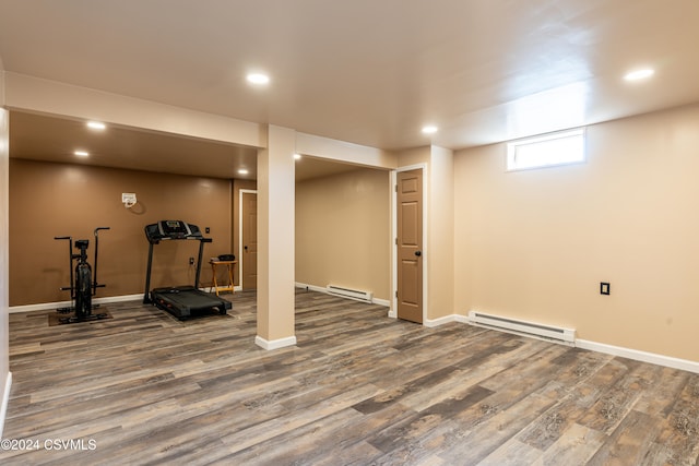 exercise area with wood-type flooring and a baseboard heating unit