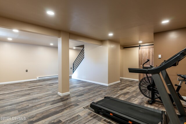 exercise area featuring a baseboard radiator, a barn door, and dark hardwood / wood-style flooring