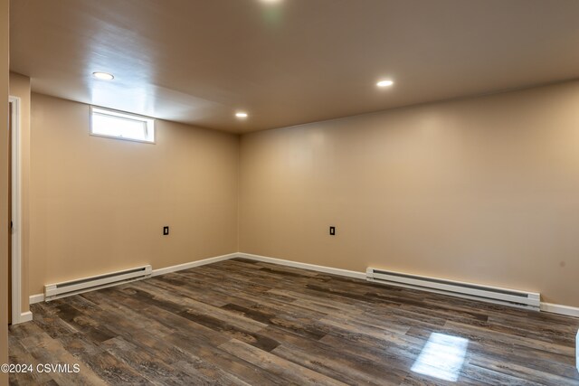 basement with dark hardwood / wood-style flooring and a baseboard heating unit