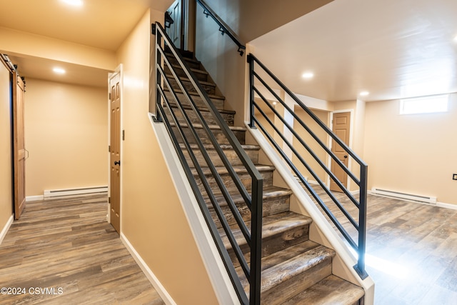 staircase featuring hardwood / wood-style floors, a baseboard radiator, and a barn door