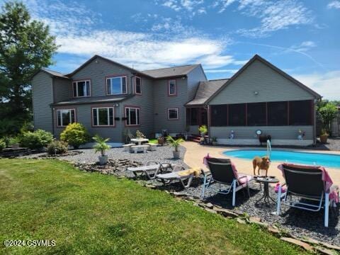 rear view of property with a yard, a patio, and a sunroom