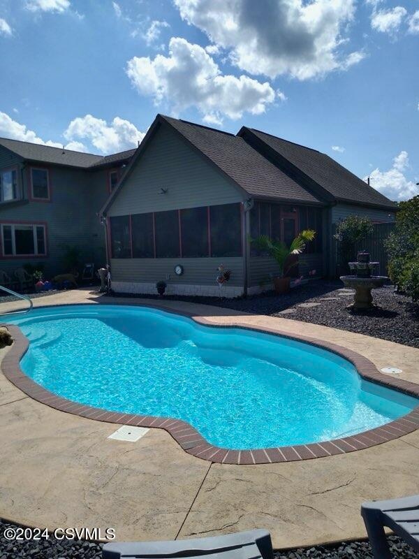 view of pool with a sunroom and a patio