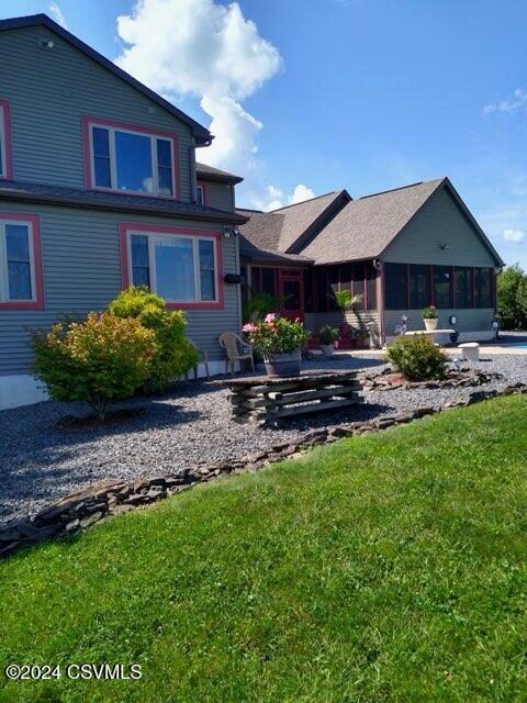 back of house featuring a sunroom and a lawn