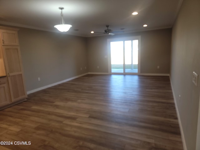 empty room featuring dark wood-type flooring, ceiling fan, and crown molding