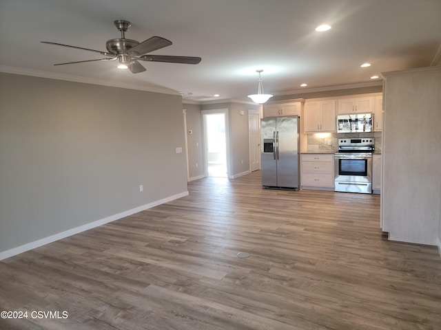 kitchen with appliances with stainless steel finishes, decorative backsplash, ceiling fan, hardwood / wood-style flooring, and ornamental molding