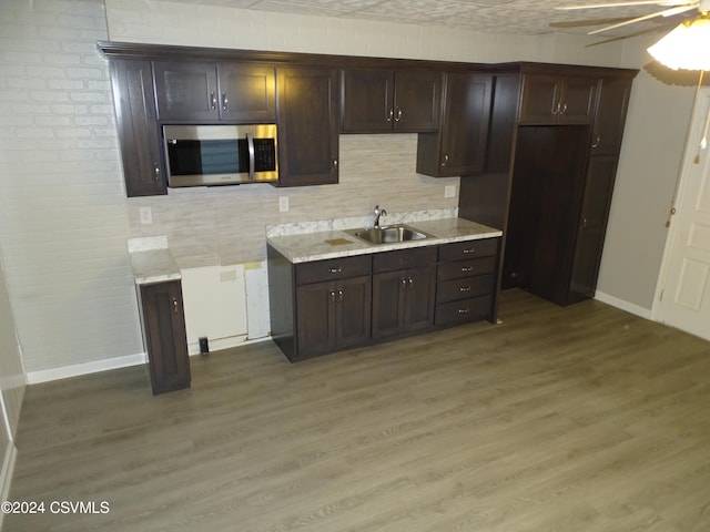 kitchen with dark brown cabinets, sink, wood-type flooring, and ceiling fan