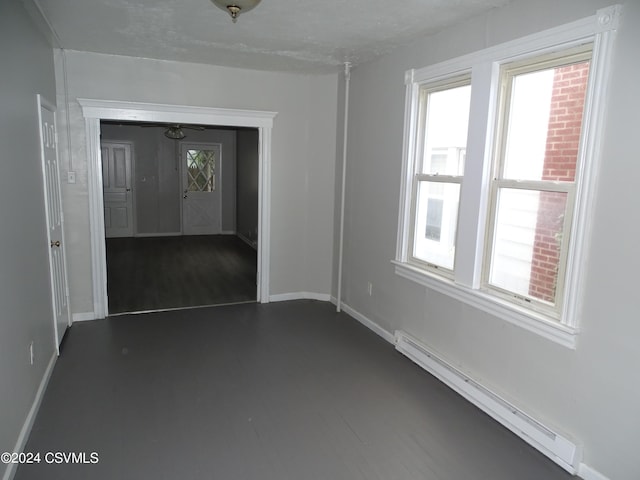 spare room featuring baseboard heating and dark hardwood / wood-style flooring