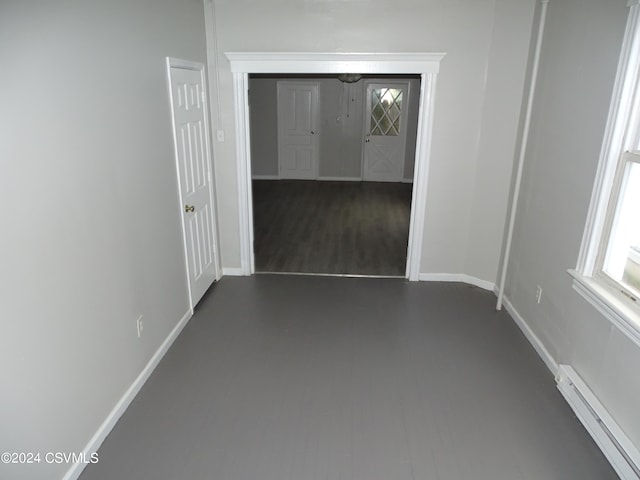 hallway with a baseboard heating unit and dark wood-type flooring