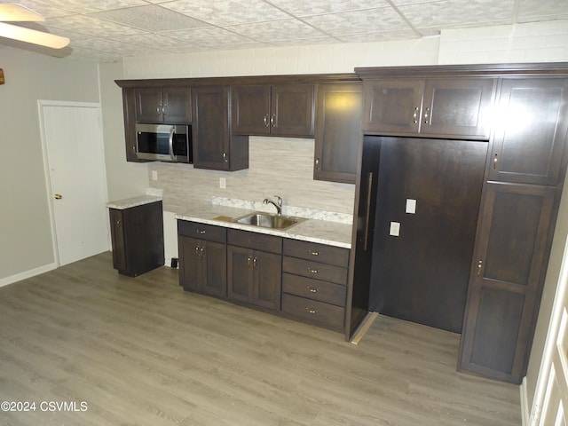 310 W 3rd St, Mount Carmel, PA 17851 - kitchen featuring decorative backsplash, dark brown cabinets, a sink, stainless steel microwave, and light wood-style floors