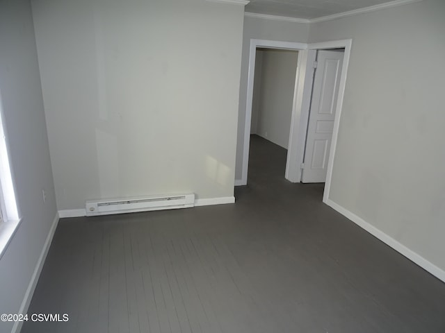 spare room with crown molding, a baseboard heating unit, and dark wood-type flooring