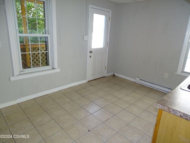 foyer entrance with light tile patterned floors, a baseboard heating unit, and a wealth of natural light