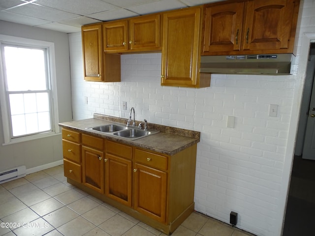 310 W 3rd St, Mount Carmel, PA 17851 - kitchen featuring brown cabinets, a sink, decorative backsplash, light tile patterned floors, and under cabinet range hood