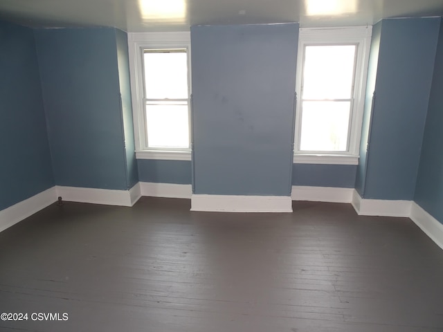 empty room with dark wood-type flooring and a healthy amount of sunlight