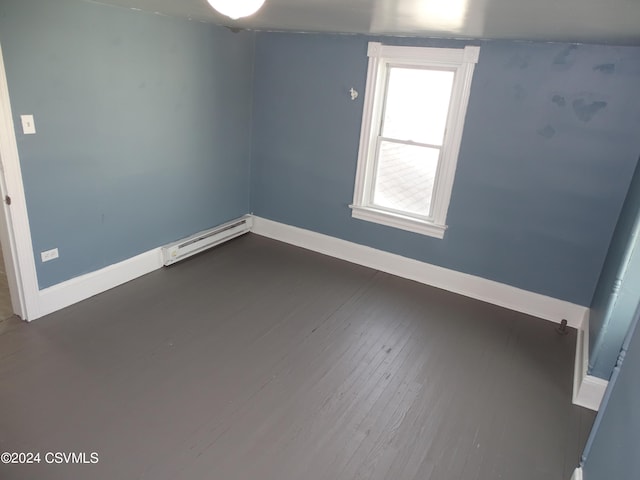 unfurnished room featuring baseboard heating and dark hardwood / wood-style flooring