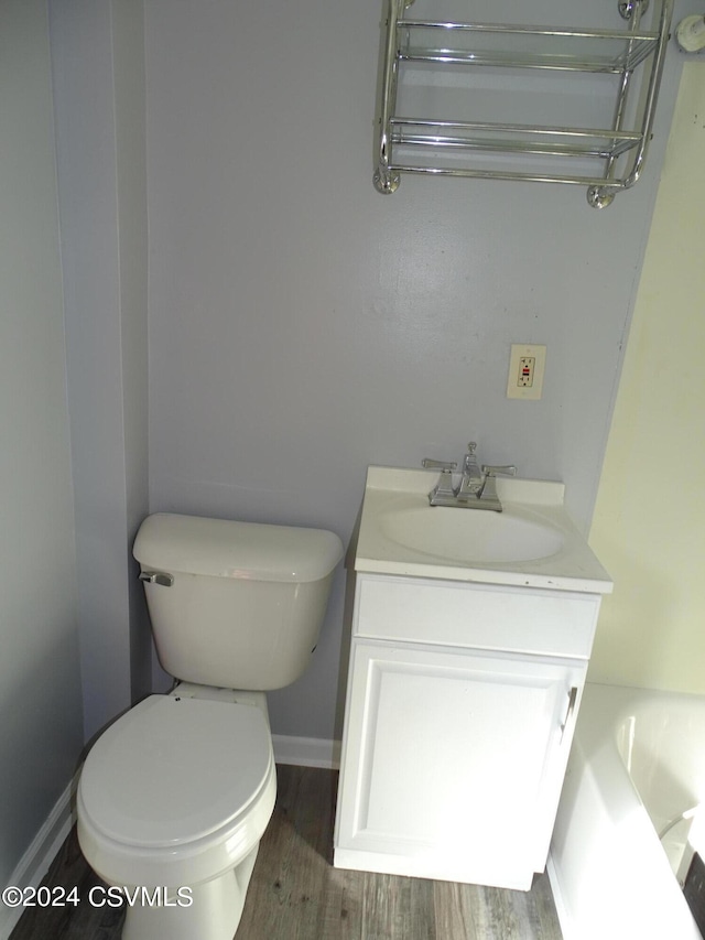 bathroom with vanity, a tub to relax in, hardwood / wood-style flooring, and toilet