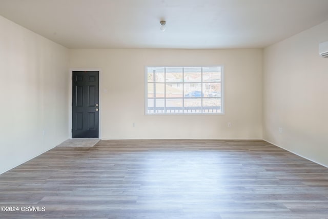 empty room with an AC wall unit and light hardwood / wood-style flooring