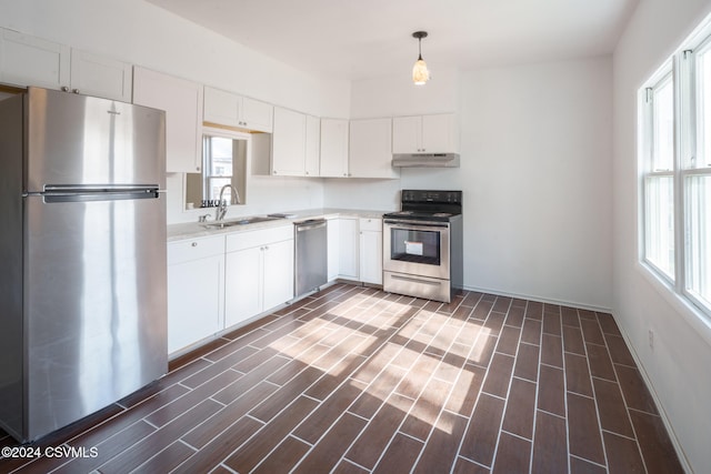 kitchen featuring dark hardwood / wood-style floors, sink, pendant lighting, white cabinetry, and appliances with stainless steel finishes