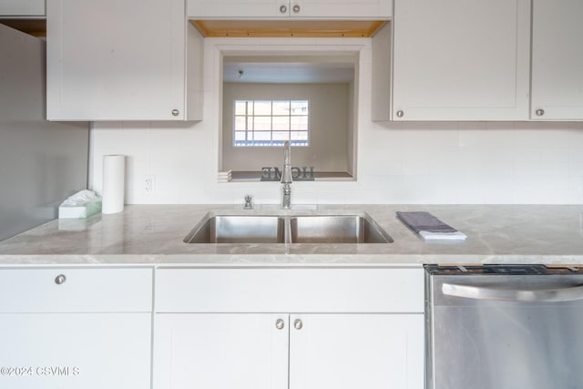 kitchen featuring decorative backsplash, white cabinets, stainless steel dishwasher, and sink