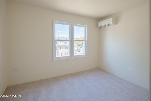 empty room featuring a wall mounted AC and light colored carpet