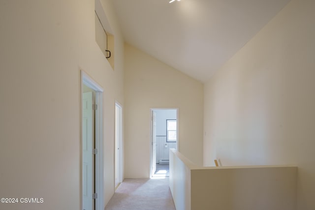 hall with light colored carpet and high vaulted ceiling