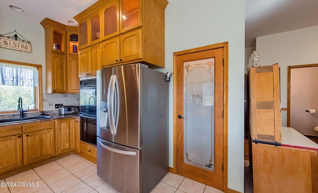 kitchen with decorative backsplash, double oven, sink, stainless steel fridge, and light tile patterned flooring