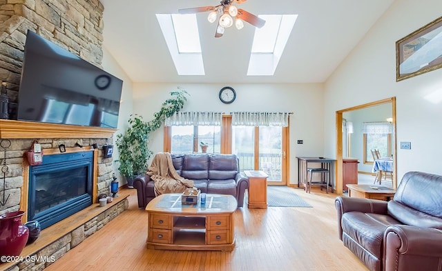 living room with a stone fireplace, high vaulted ceiling, light wood-type flooring, and ceiling fan