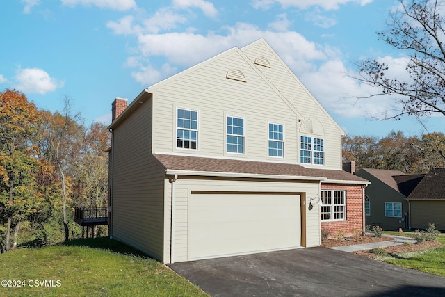 view of side of property featuring an attached garage, aphalt driveway, a yard, and a chimney