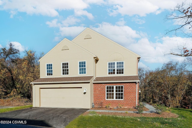 traditional-style house with an attached garage, a shingled roof, driveway, and brick siding