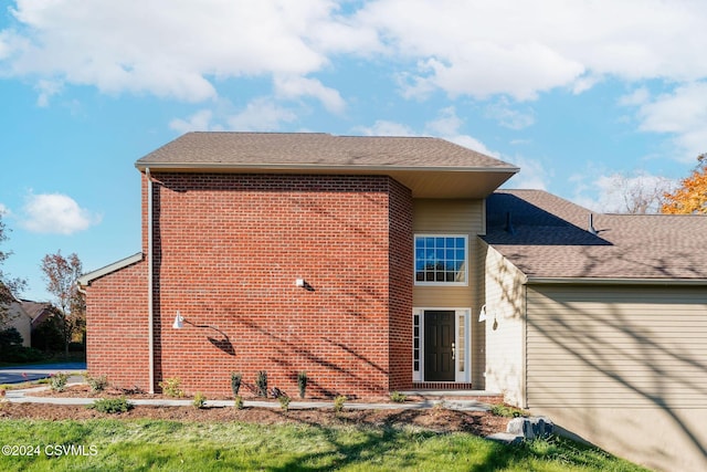 back of property featuring brick siding, a garage, roof with shingles, and driveway