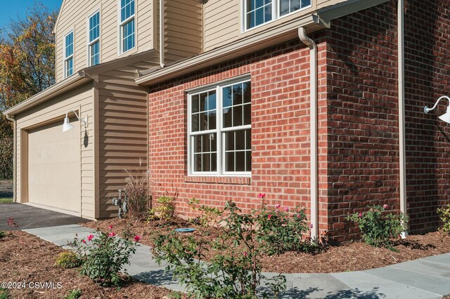 view of side of home featuring brick siding, driveway, and a garage
