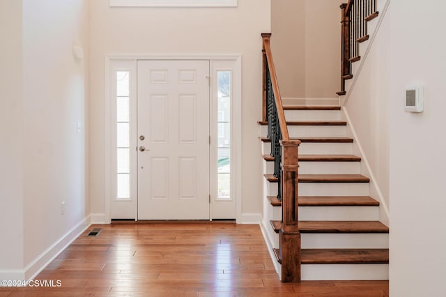 entrance foyer with visible vents, a wealth of natural light, hardwood / wood-style flooring, and stairway