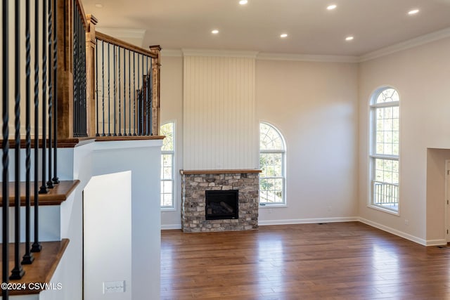 unfurnished living room with ornamental molding, dark wood-type flooring, and a stone fireplace