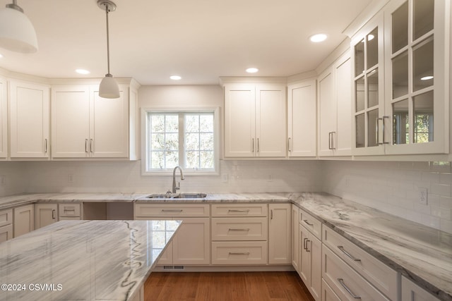 kitchen with sink, dark hardwood / wood-style flooring, decorative light fixtures, white cabinets, and light stone counters