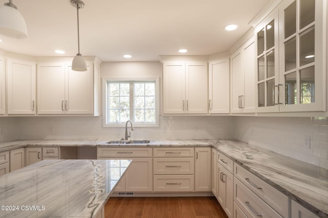 kitchen featuring a sink, glass insert cabinets, tasteful backsplash, and white cabinets