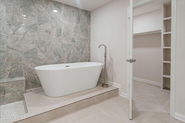 full bath featuring a walk in shower, tile walls, a spacious closet, and a soaking tub