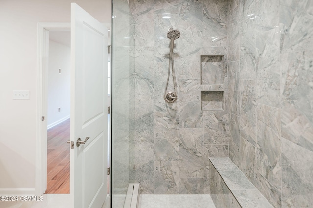 bathroom with wood-type flooring and tiled shower